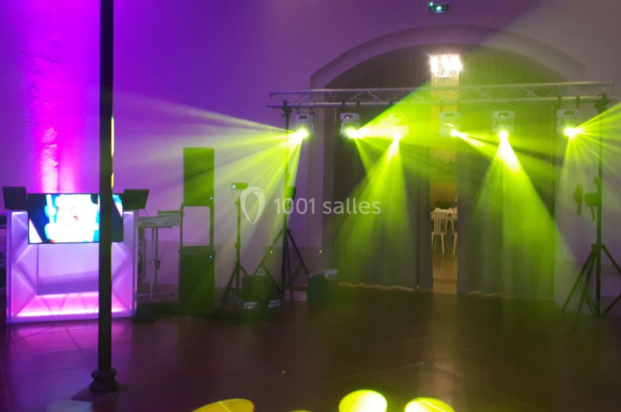 Installation de matériel de sonorisation et éclairage avec projecteurs colorés dans une salle événementielle.