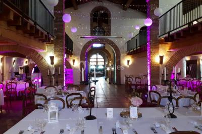 Salle de réception décorée avec des lumières colorées, des lanternes suspendues et un espace pour la musique et la danse.