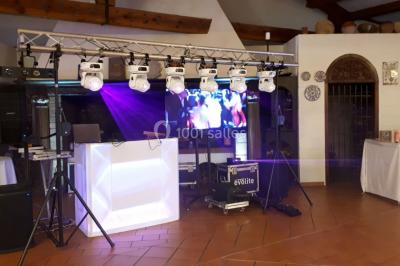 Salle de réception décorée avec des lumières colorées, des lanternes suspendues et un espace pour la musique et la danse.
