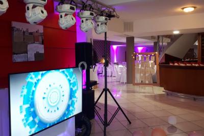 Salle de réception décorée avec des lumières colorées, des lanternes suspendues et un espace pour la musique et la danse.