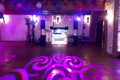 Salle de réception décorée avec des lumières colorées, des lanternes suspendues et un espace pour la musique et la danse.