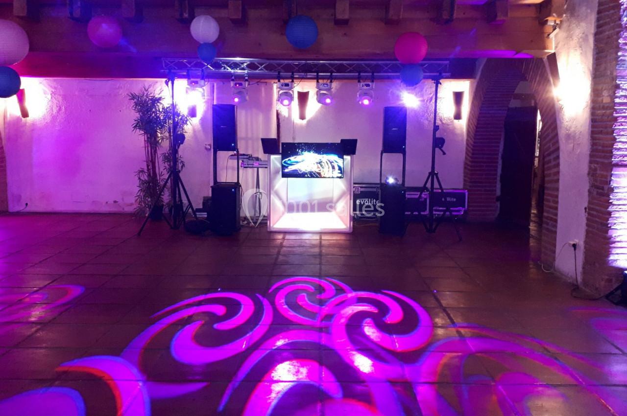 Salle de réception décorée avec des lumières colorées, des lanternes suspendues et un espace pour la musique et la danse.