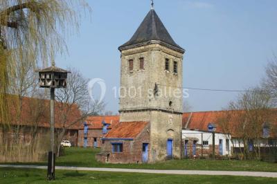 Miniature Location salle Clairmarais (Pas-de-Calais) - La Ferme de l'Abbaye #13 Façade d'une grange en briques avec porte en bois rouge, toit en tuiles et piles de bois empilées sur les côtés.