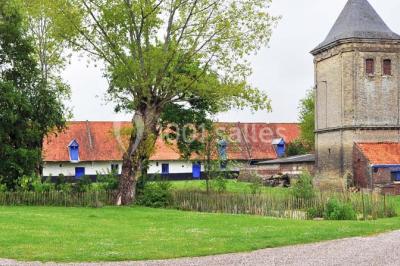 Miniature Location salle Clairmarais (Pas-de-Calais) - La Ferme de l'Abbaye #3 Façade d'une grange en briques avec porte en bois rouge, toit en tuiles et piles de bois empilées sur les côtés.