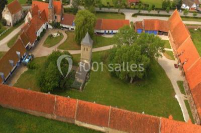 Miniature Location salle Clairmarais (Pas-de-Calais) - La Ferme de l'Abbaye #2 Façade d'une grange en briques avec porte en bois rouge, toit en tuiles et piles de bois empilées sur les côtés.
