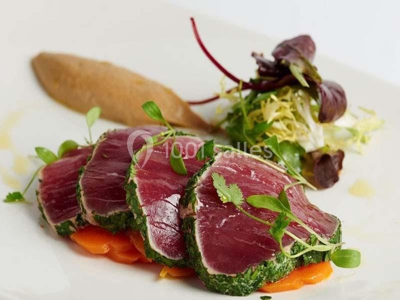 Tranches de thon mi-cuit en croûte d'herbes, accompagnées de légumes et d'une purée en présentation soignée.