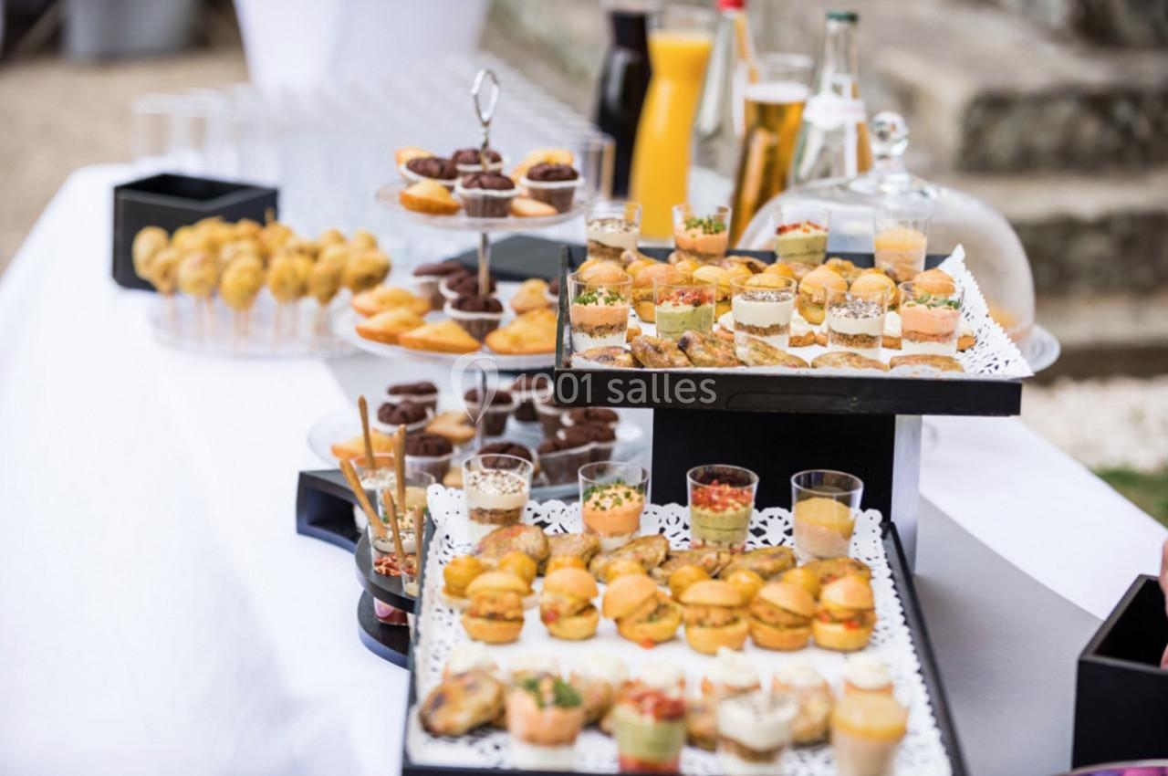 Table garnie de bouchées salées et sucrées, présentées sur des plateaux et accompagnées de boissons.