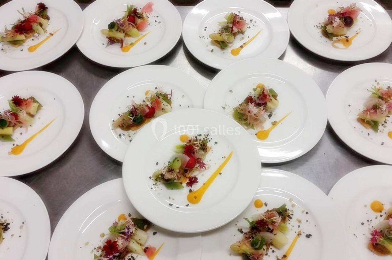 Assiettes dressées avec des entrées colorées, décorées de légumes, herbes et traits de sauce sur une table.