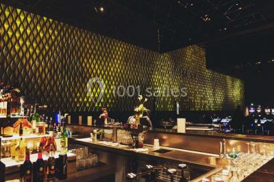Salle de restaurant moderne avec des tables dressées, des chaises orange et un éclairage chaleureux.