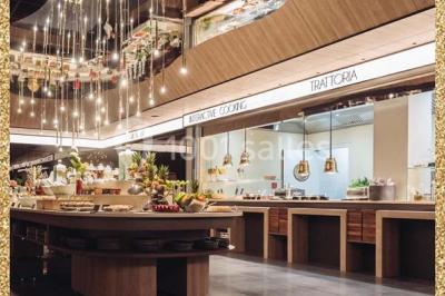 Salle de restaurant moderne avec des tables dressées, des chaises orange et un éclairage chaleureux.