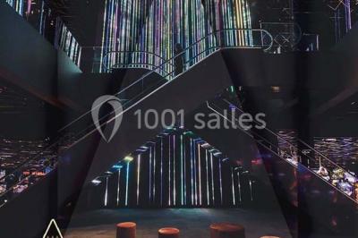 Salle de restaurant moderne avec des tables dressées, des chaises orange et un éclairage chaleureux.