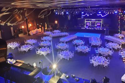Salle de restaurant moderne avec des tables dressées, des chaises orange et un éclairage chaleureux.