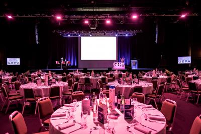 Salle de restaurant moderne avec des tables dressées, des chaises orange et un éclairage chaleureux.