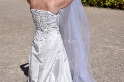 Miniature Claire Avias Créations #9 Mannequin vêtu d'une robe en dentelle blanche avec un voile noir couvrant la tête, devant une porte en bois clair.