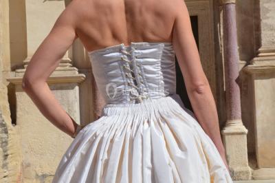 Miniature Claire Avias Créations #11 Mannequin vêtu d'une robe en dentelle blanche avec un voile noir couvrant la tête, devant une porte en bois clair.