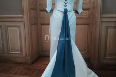 Miniature Claire Avias Créations #14 Mannequin vêtu d'une robe en dentelle blanche avec un voile noir couvrant la tête, devant une porte en bois clair.