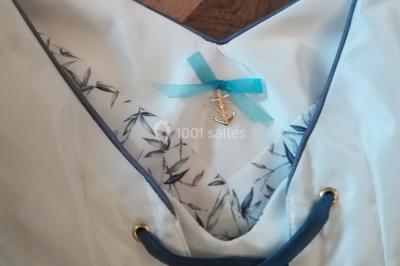 Miniature Claire Avias Créations #16 Mannequin vêtu d'une robe en dentelle blanche avec un voile noir couvrant la tête, devant une porte en bois clair.