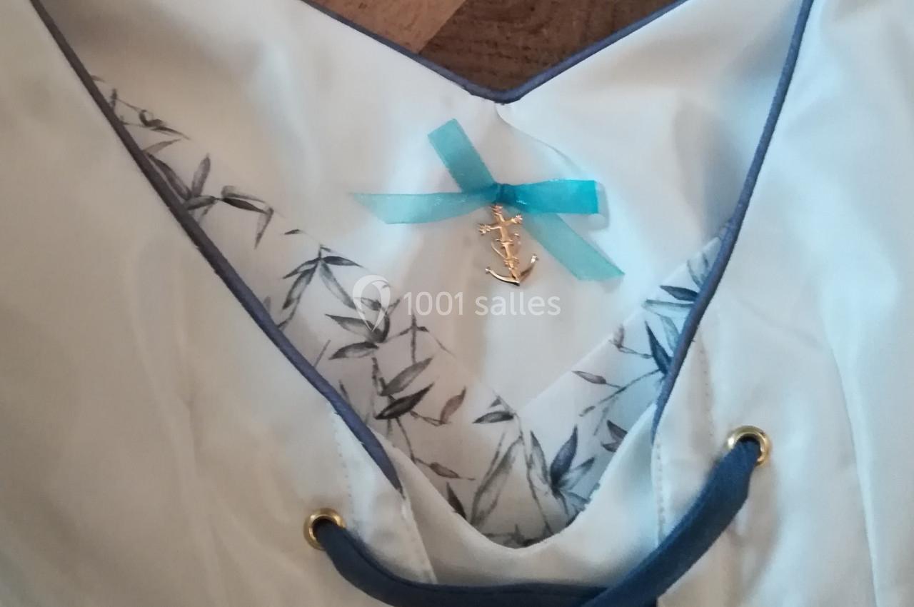 Corsage blanc avec laçage bleu, doublure imprimée de motifs végétaux et ornement en forme d'ancre marine.