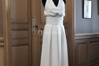 Miniature Claire Avias Créations #22 Mannequin vêtu d'une robe en dentelle blanche avec un voile noir couvrant la tête, devant une porte en bois clair.