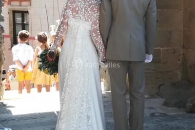 Miniature Claire Avias Créations #24 Mannequin vêtu d'une robe en dentelle blanche avec un voile noir couvrant la tête, devant une porte en bois clair.