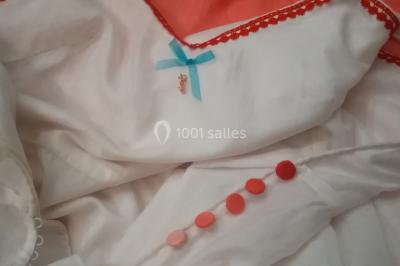 Miniature Claire Avias Créations #26 Mannequin vêtu d'une robe en dentelle blanche avec un voile noir couvrant la tête, devant une porte en bois clair.