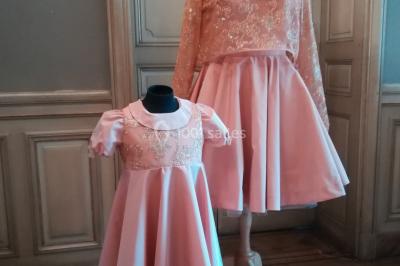 Miniature Claire Avias Créations #27 Mannequin vêtu d'une robe en dentelle blanche avec un voile noir couvrant la tête, devant une porte en bois clair.