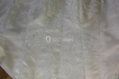 Miniature Claire Avias Créations #34 Mannequin vêtu d'une robe en dentelle blanche avec un voile noir couvrant la tête, devant une porte en bois clair.