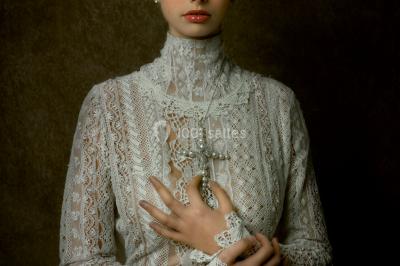 Miniature Claire Avias Créations #37 Mannequin vêtu d'une robe en dentelle blanche avec un voile noir couvrant la tête, devant une porte en bois clair.