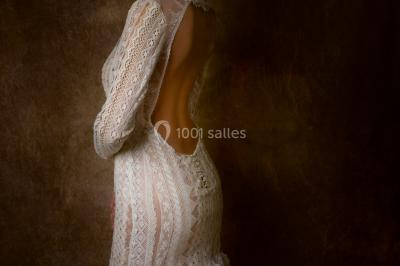 Miniature Claire Avias Créations #38 Mannequin vêtu d'une robe en dentelle blanche avec un voile noir couvrant la tête, devant une porte en bois clair.