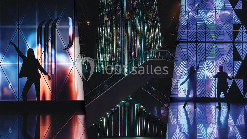 Personnes dans un espace futuriste avec des murs lumineux et des motifs géométriques colorés.