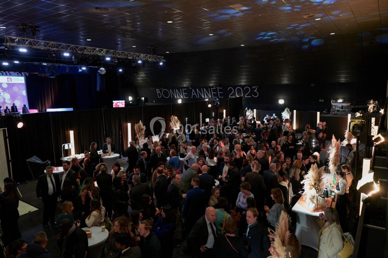 Foule rassemblée dans une salle événementielle décorée, avec l'inscription ’Bonne Année 2023’ en arrière-plan.