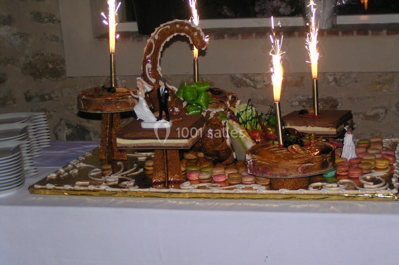 Pièce montée décorée avec des macarons, des figurines et des cierges étincelants sur une table blanche.
