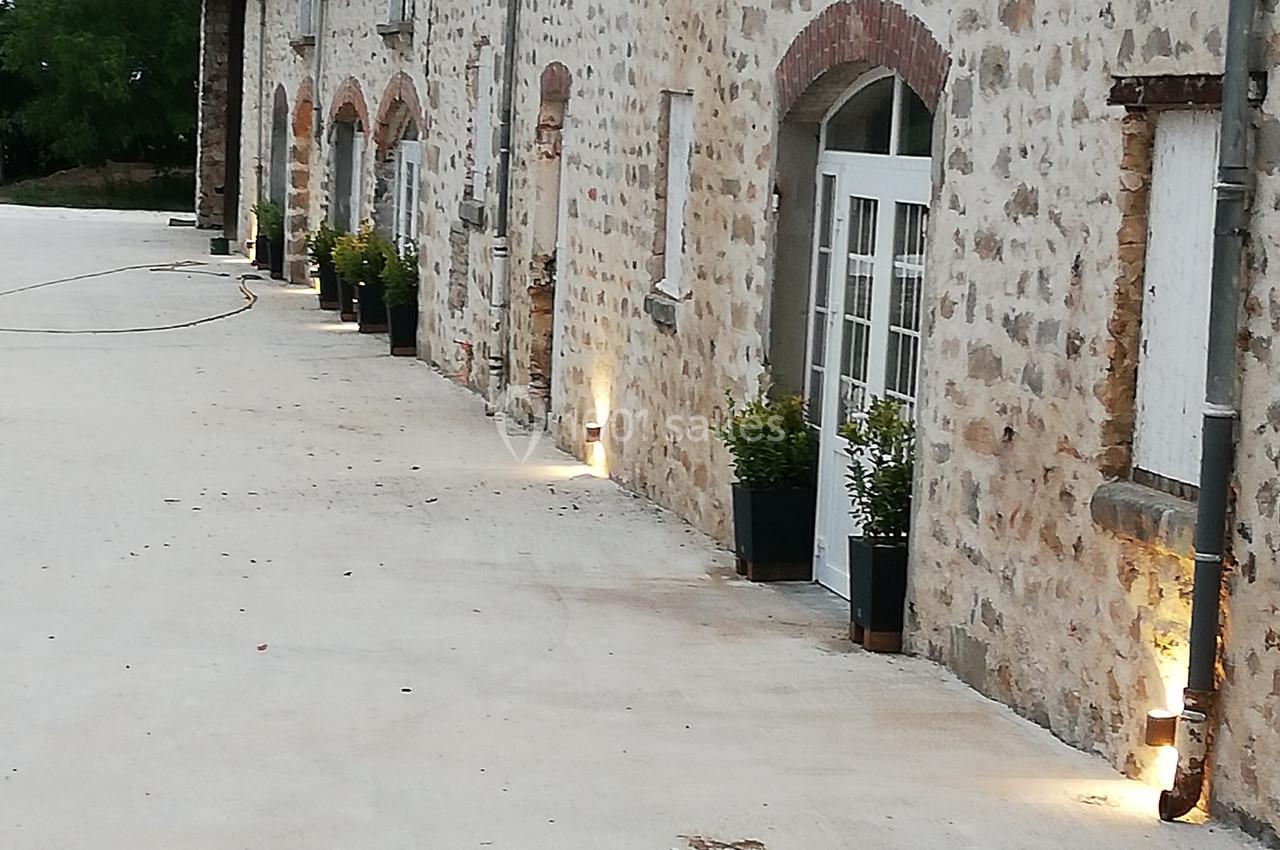 Façade en pierre d'une maison avec des portes vitrées, des plantes en pots et un éclairage extérieur au sol.