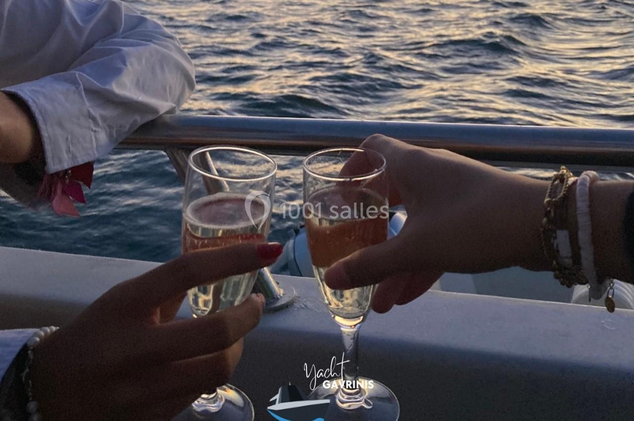 Deux personnes trinquent avec des coupes de champagne sur un bateau au coucher du soleil.