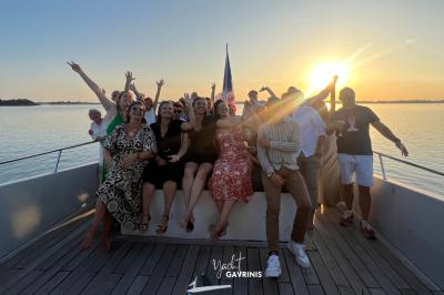 Mobilier en rotin noir avec coussins blancs sur une terrasse en bois couverte, vue sur l'extérieur urbain.