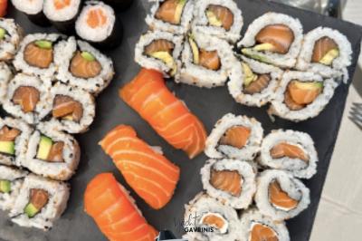 Mobilier en rotin noir avec coussins blancs sur une terrasse en bois couverte, vue sur l'extérieur urbain.