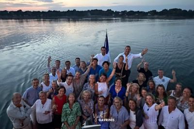 Mobilier en rotin noir avec coussins blancs sur une terrasse en bois couverte, vue sur l'extérieur urbain.