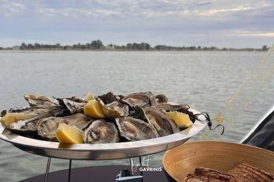 Mobilier en rotin noir avec coussins blancs sur une terrasse en bois couverte, vue sur l'extérieur urbain.