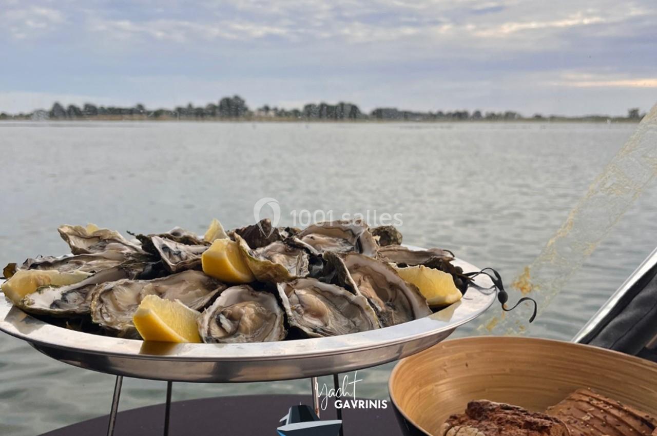 Plateau d'huîtres fraîches avec quartiers de citron, posé sur une table en bord de mer par temps nuageux.