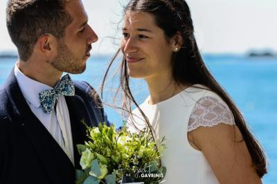 Mobilier en rotin noir avec coussins blancs sur une terrasse en bois couverte, vue sur l'extérieur urbain.