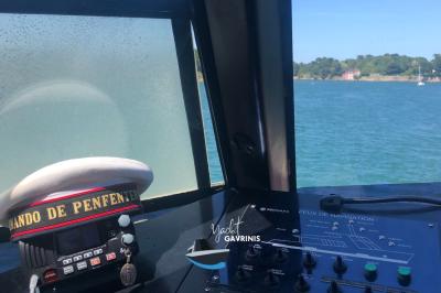 Mobilier en rotin noir avec coussins blancs sur une terrasse en bois couverte, vue sur l'extérieur urbain.