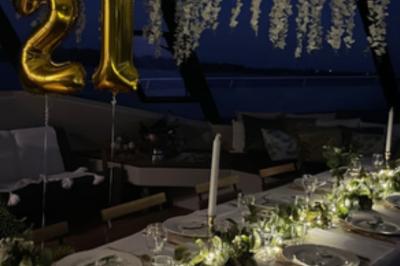 Mobilier en rotin noir avec coussins blancs sur une terrasse en bois couverte, vue sur l'extérieur urbain.