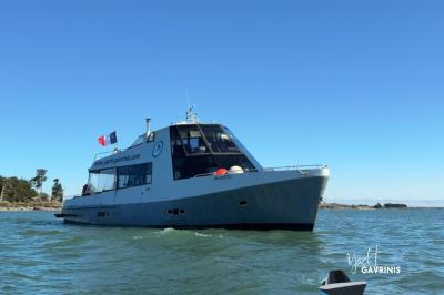 Mobilier en rotin noir avec coussins blancs sur une terrasse en bois couverte, vue sur l'extérieur urbain.