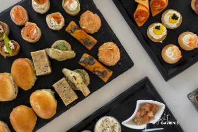 Mobilier en rotin noir avec coussins blancs sur une terrasse en bois couverte, vue sur l'extérieur urbain.