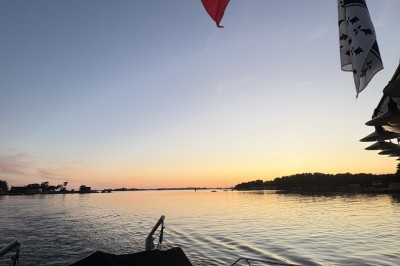 Vue depuis un bateau avec un siège orange au premier plan et un paysage côtier en arrière-plan.