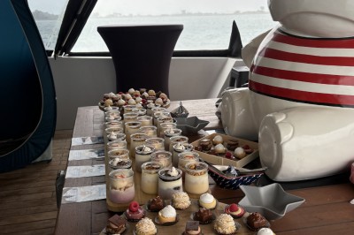 Vue depuis un bateau avec un siège orange au premier plan et un paysage côtier en arrière-plan.