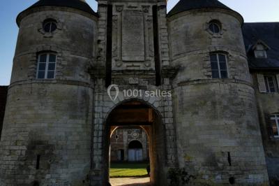 Miniature Entrée Façade avant du Château  Pièce rustique avec murs en pierre, plafond en bois, réservoir métallique rouge et mobilier simple.