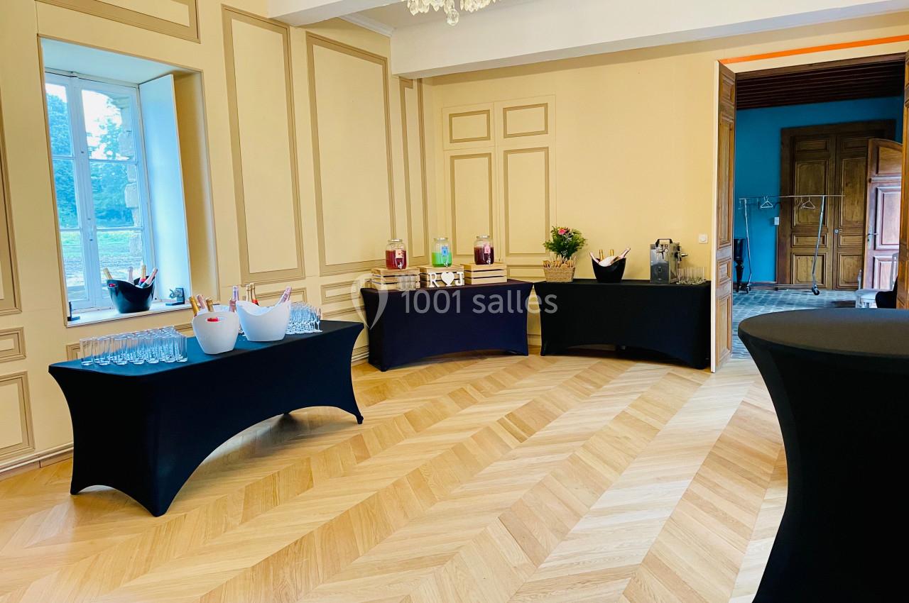 Salle élégante avec parquet clair, tables nappées de noir disposées pour un buffet, et lumière naturelle provenant d'une…
