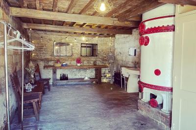 Miniature WC  Pièce rustique avec murs en pierre, plafond en bois, réservoir métallique rouge et mobilier simple.