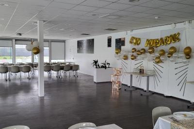 Miniature Location salle Bonneuil-sur-Marne (Val-de-Marne) - La Caravelle #16 Centre de table avec bougies torsadées, fleurs colorées et nappe orange, entouré de verres et couverts.